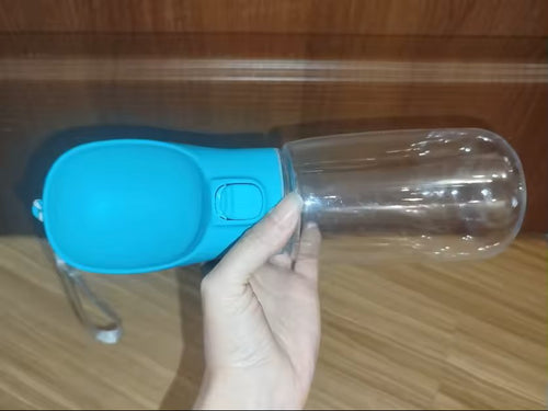 The blue dog water bottle held sideways, with the press button clearly visible