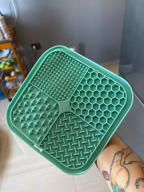 The green lick mat held in one hand, showing the four groove patterns close up
